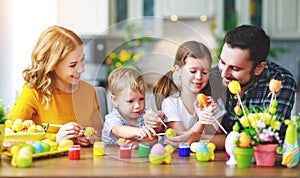 Happy easter! family mother, father and children paint eggs for holiday