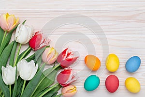 Happy Easter frame border, paschal eggs on a white wood background, bouquet of tulips, floral card, colorful festive template with