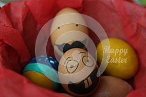 Happy Easter. Funny face painted on Easter eggs in a red basket decoration. Happy Easter Day concept, with card greeting text.