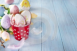 Happy Easter gingerbread cookie eggs with bucket and tulips with colorful eggs on blue wood background,