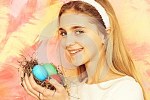 Happy easter girl with colorful painted eggs in straw nest