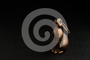Happy Easter, gold metal bunny on a black background looking up adoringly