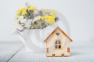 Happy Easter greeting card. Miniature wooden house. Rabbits, colorful eggs, spring flowers with tag for text..