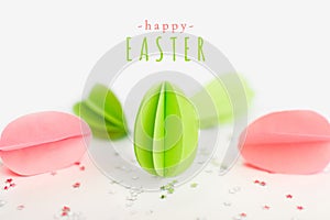 Happy Easter greeting card with text and handmade paper green and pink eggs against of silver stars on white background. DIY,