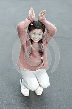 Happy easter. Holiday bunny girl posing like rabbit grey background. Child smiling play bunny role. Playful baby