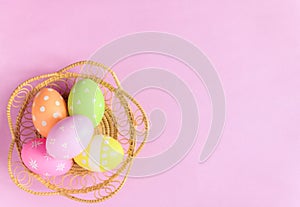 Happy Easter holiday greeting card concept. Colorful Easter Eggs and spring flowers on pastel pink background. Flat lay, top view