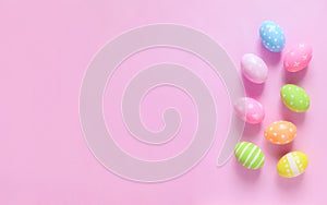 Happy Easter holiday greeting card concept. Colorful Easter Eggs and spring flowers on pastel pink background. Flat lay, top view