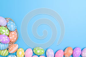 Happy Easter holiday greeting card design concept. Colorful Easter Eggs and spring flowers on blue background. Flat lay, top view