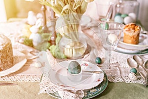 happy easter holiday in springtime. painted green emerald colored chicken egg in bowl and plate on table
