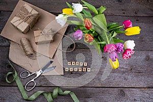 Happy Easter inscription in wooden letters. Gift wrapping. Mix of spring tulips flowers. Background with flowers tulips