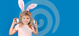 Happy Easter. Kids boy in bunny ears hunting easter eggs isolated on blue background. Wide photo banner for website