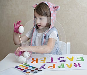 Happy easter little girl painter in pink bunny ears with colorful painted eggs. A kid preparing for Easter. Painted hand