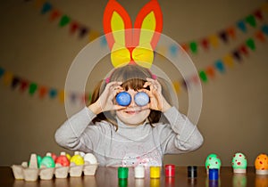 Happy easter. Little girl with rabbit ears and big funny eggs eyes painted eggs. Kid preparing for Easter. Painted hand. Art and
