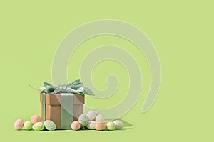 Easter tiny eggs sweets and gift box on green background.