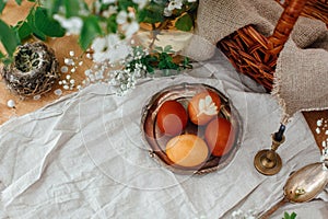 Happy Easter. Modern Easter eggs on vintage plate on rustic table with spring flowers,candle, basket. Stylish red and yellow