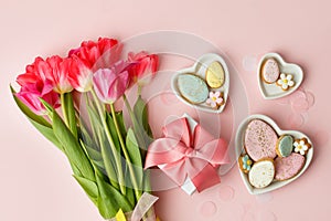 Happy Easter. Multi-colored pastel easter cookies gingerbread, gift box seasonal flowers tulips on pink background. Easter concept