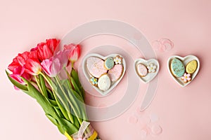 Happy Easter. Multi-colored pastel easter cookies gingerbread, seasonal flowers tulips on pink background. Easter concept, copy