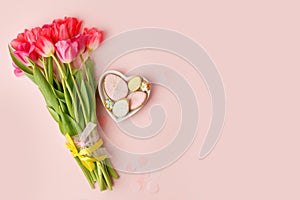 Happy Easter. Multi-colored pastel easter cookies gingerbread, seasonal flowers tulips on pink background. Easter concept, copy