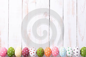 Happy easter! Row Easter eggs with colorful paper flowers on white wooden background