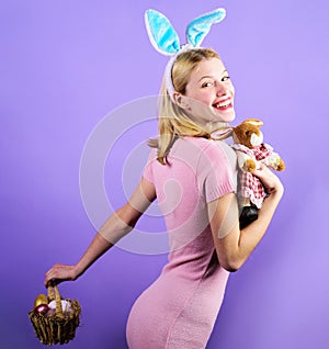 Happy easter. Smiling Girl with bunny toy and basket with colorful eggs. Woman with Plush rabbit.