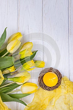Happy Easter. Spring flowers yellow daffodils and tulips, easter eggs and candle on a white background. Top view, free space