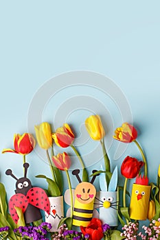 Happy easter spring toy collection and fresh flowers on blue background, kids holiday party concept background. Paper crafts, DIY