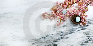 Happy Easter with springtime cherry blossoms and small bird nest with one egg inside on stone background in flat lay format