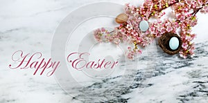 Happy Easter with springtime cherry blossoms and small bird nest with one egg inside on stone background in flat lay format plus