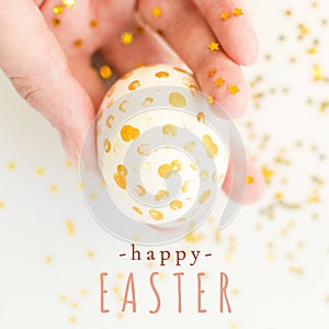 Happy Easter square greeting card with message. Closeup handpainted white egg with gold dots in female hand with gold stars