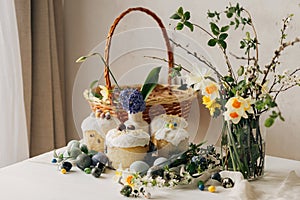 Happy Easter! Stylish easter eggs, easter bread, basket and spring flowers on linen napkin on rustic table. Natural painted marble