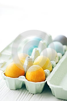 Happy Easter. Stylish Easter eggs in rainbow pastel colors in carton tray on white wooden background, space for text. Modern