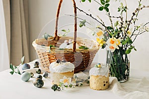 Happy Easter! Stylish easter natural dyed eggs, bread, basket with food and spring flowers on rustic table. Traditional easter