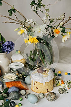 Happy Easter! Stylish easter natural dyed eggs, meat, bread, butter, beets, basket and flowers on rustic table. Traditional easter