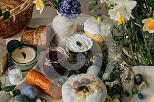 Happy Easter! Stylish easter natural dyed eggs, meat, bread, butter, beets, basket and flowers on rustic table. Traditional easter