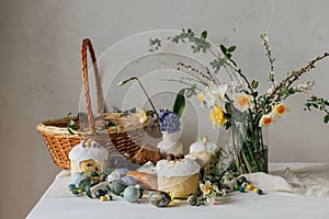 Happy Easter! Stylish easter natural dyed eggs, meat, bread, butter, beets, basket and flowers on rustic table. Traditional easter