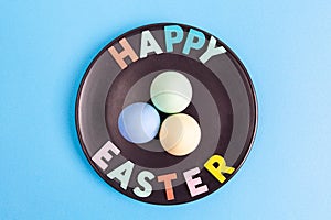 Happy Easter text with colorful eggs arranged on black plate.