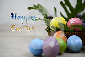 Happy Easter text and decoration with white background of colorful easteregg on wooden rattan basket and green leaves. Easter eggs