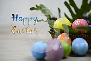 Happy Easter text and decoration with white background of colorful easteregg on wooden rattan basket and green leaves. Easter eggs photo