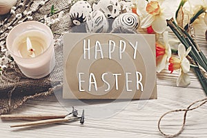 Happy easter text. flowers daffodils and stylish eggs on rustic