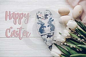 happy easter text greeting card sign on stylish white tulips easter eggs and bunny floral heart on rustic wooden background top v