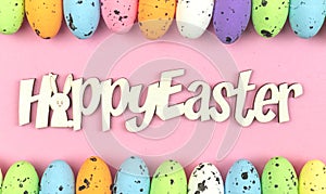 Happy Easter text message on pastel pink background decorated with colorful easter eggs