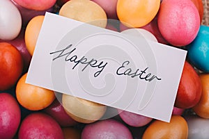 Happy Easter written on a small piece of paper on colorful decor