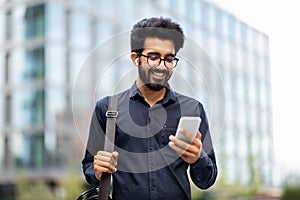 Happy eastern man manager going to office, using phone