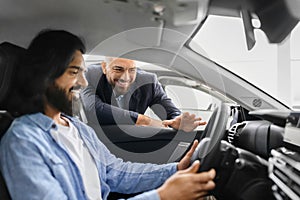 Happy eastern man sitting in car listening to sales manager