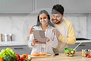 Happy eastern man and woman using tablet white cooking