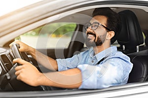 Happy eastern young businessman driving new auto