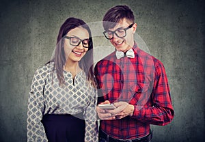 Happy eccentic hipster guy holding smart phone, showing his girlfriend funny pictures