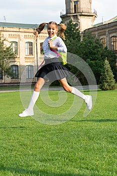 Happy ecstatic kid in uniform back to school jumping for joy, September 1