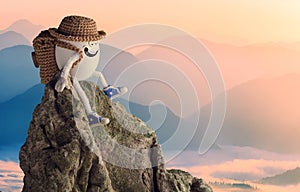 Happy egg hiker in a funny hat sitting on a cliff