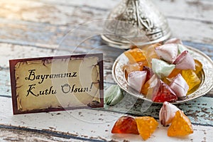 Happy Eid text in turkish on vintage table with sugar candies